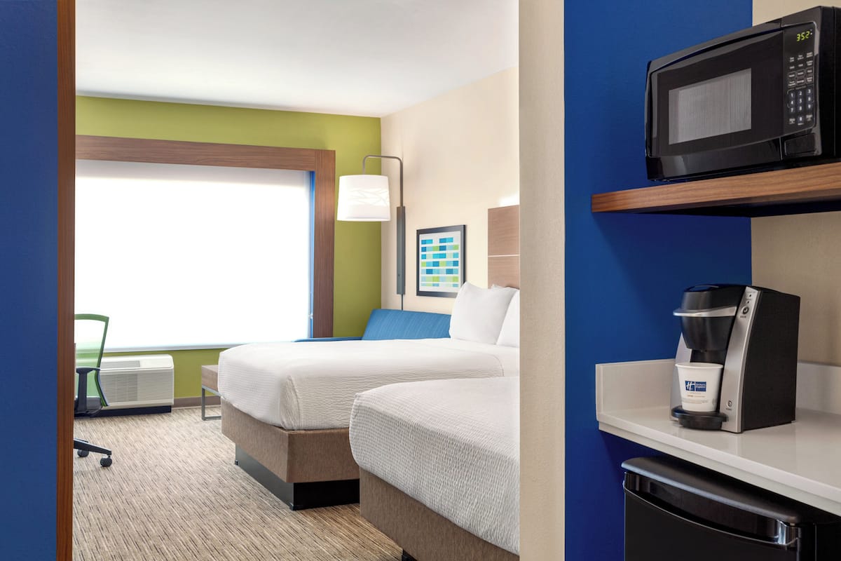 A hotel room with two beds, a microwave, a coffee maker, and a window with a view.