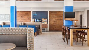 Un espace de détente moderne, doté de sièges confortables, d’un bar à café et d’un téléviseur.