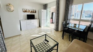 A modern living space with a kitchen, dining area, and a large window offering a city view.