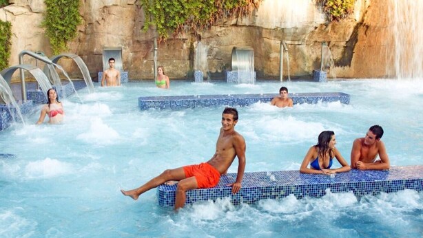 A pool area with multiple hot tubs and a waterfall feature.