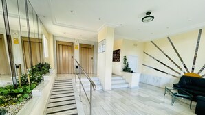 A hotel lobby with a marble staircase, a reception desk, and a seating area.