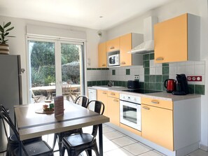 Cozinha moderna com área de refeições, micro-ondas, chaleira e máquina de lavar louça.