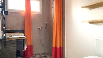 A bathroom with a shower, a toilet, a sink, and a window.