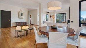 Un comedor moderno con una mesa redonda de madera, sillas blancas e iluminación colgante.