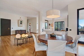 Un espace repas moderne avec une table ronde en bois, des chaises blanches et des luminaires suspendus.