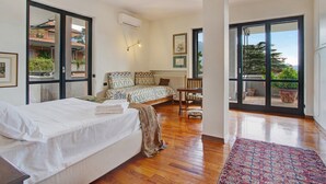 Un dormitorio con cama, sofá, mesa y vistas a través de un ventanal.