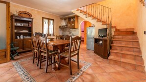 A spacious kitchen with a dining table, chairs, and a staircase leading to an upper level. - Vacation Home Casa Giovanna e Antonio with Sea View, A/C, Terrace & Garden (Calasetta)