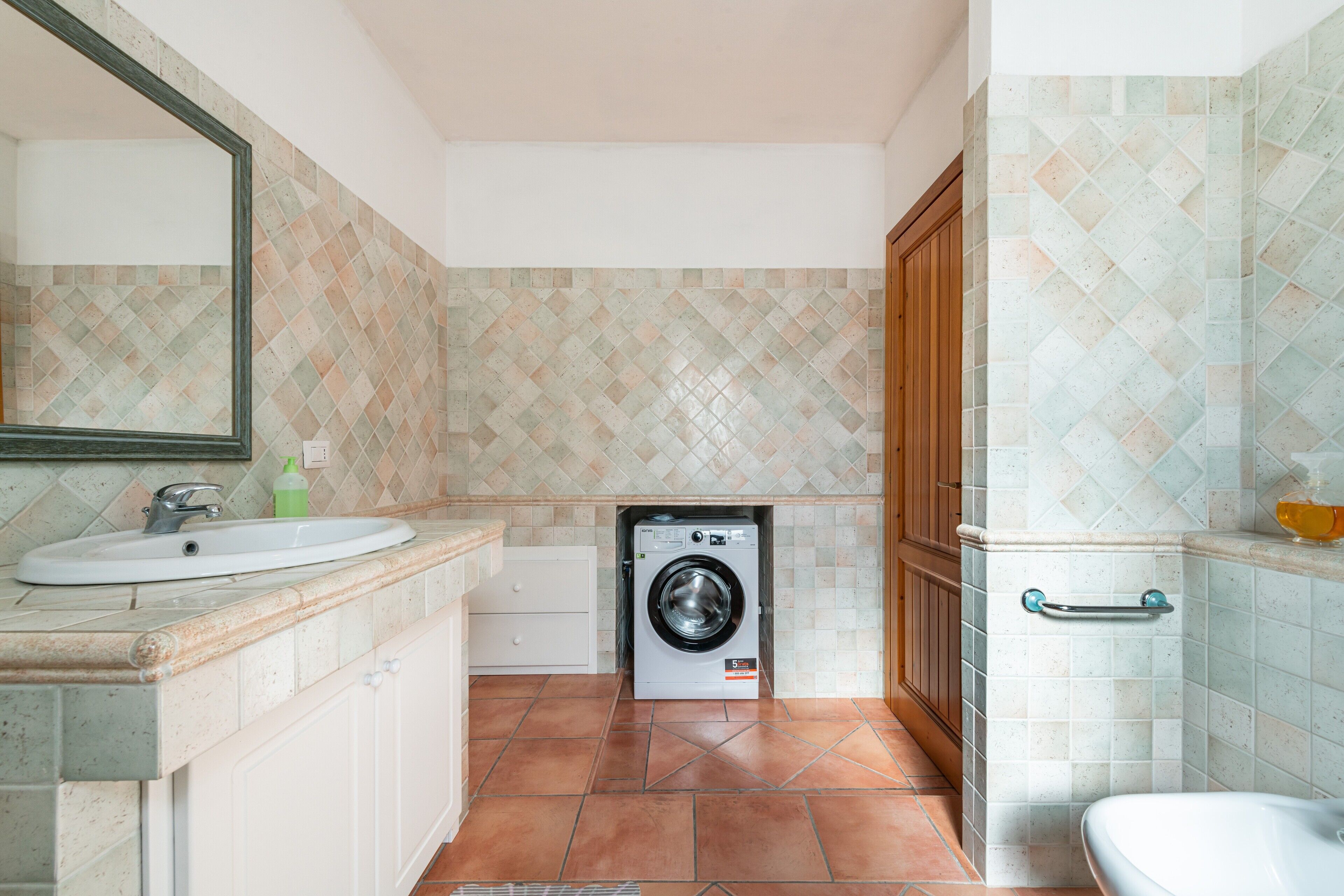 Ein Badezimmer mit Waschbecken, Spiegel, Waschmaschine und Toilette.