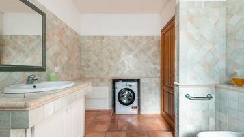 Ein Badezimmer mit Waschbecken, Spiegel, Waschmaschine und Toilette.