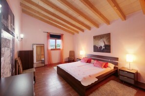 Un dormitorio con una cama grande, vigas de madera en el techo, un cuadro en la pared y una silla.