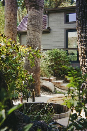 A modern building with a sloped roof, surrounded by mature trees and a well-maintained garden with a stone pathway. - Castle HOT Springs (MORRISTOWN)
