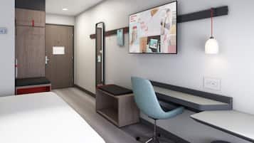 A modern hotel room with a bed, a desk, a chair, a wardrobe, and a wall-mounted TV.