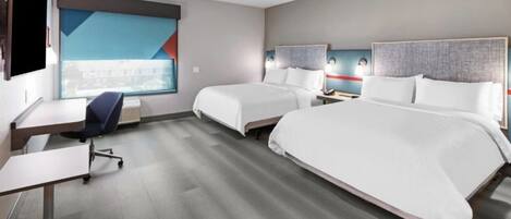 A hotel room with two beds, a desk, and a chair.