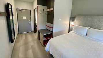 A hotel room with a bed, a wardrobe, a mirror, and a bedside table.