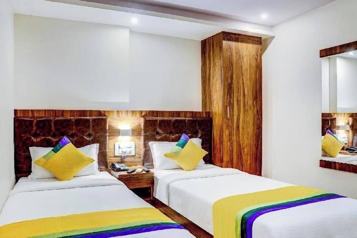 A hotel room with two beds, wooden headboards, and a large mirror.
