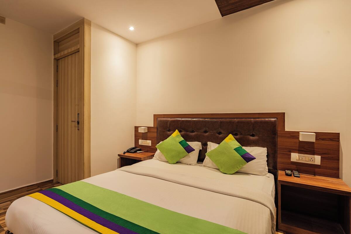 A hotel room with a bed, a nightstand, a wooden wardrobe, and a ceiling light.