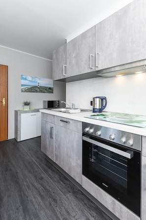 A modern kitchen with grey cabinetry, a built-in oven, and a microwave.