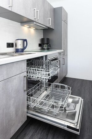 Eine moderne Küche mit grauen Schränken, einem eingebauten Geschirrspüler und einer Kaffeemaschine auf der Arbeitsplatte.