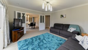 Ein Wohnzimmer mit Fernseher, Sofa und blauem Teppich.