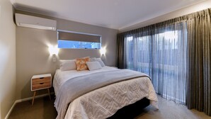 Ein Schlafzimmer mit Bett, Nachttisch, Fenster und Vorhängen.