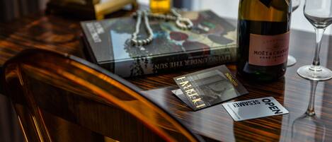 Una mesa de madera con una botella de Moët & Chandon, una copa, un libro y una tarjeta encima.