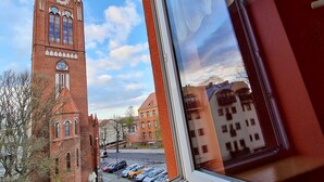 Näköala korkealle, tiilestä rakennetulle tornille, jossa on kello, ja näkymä avautuu ikkunasta, jonka lasissa on kukka-aiheinen kuvio.