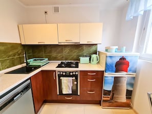 Cocina compacta con estufa, horno y una pequeña encimera.