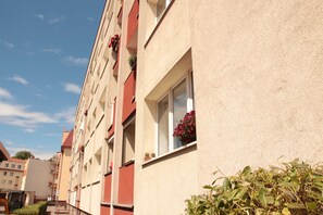 Une rangée d’immeubles à étages, dotés de balcons, dont certains sont ornés de plantes en pot.