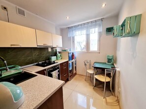 Une cuisine de taille réduite, équipée d’une cuisinière, d’un évier et d’un petit coin repas avec une table et des chaises.
