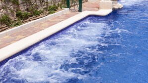 A hot tub with a tiled edge and a stone wall in the background. - Ad Hoc Vitae Retreats & Health - Adults Only (Beniarbeig)