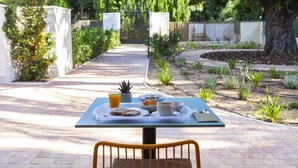 A table set outdoors with breakfast items, a chair, and a garden path in the background. - Ad Hoc Vitae Retreats & Health - Adults Only (Beniarbeig)