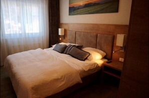 Relax in a spacious room with a large bed, two bedside tables, and a lamp on each.