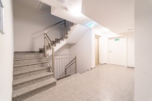 Stairs lead to an upper level, flanked by plain walls and a door with an emergency exit sign.