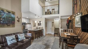 A spacious living area with a high ceiling, a dining table, and a kitchen in the background. - Crestview 30: Free EV Charger, Walk to The Village (Mammoth Lakes)