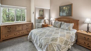 A bedroom with a large bed, wooden dresser, two bedside tables with lamps, a mirror, and a painting on the wall. - Crestview 30: Free EV Charger, Walk to The Village (Mammoth Lakes)