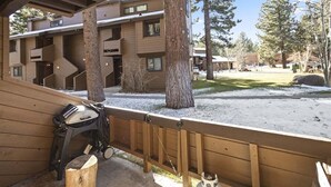 Un molo di legno con una carrozzina e una panchina, affacciato su un edificio con numerose finestre e terreno innevato.