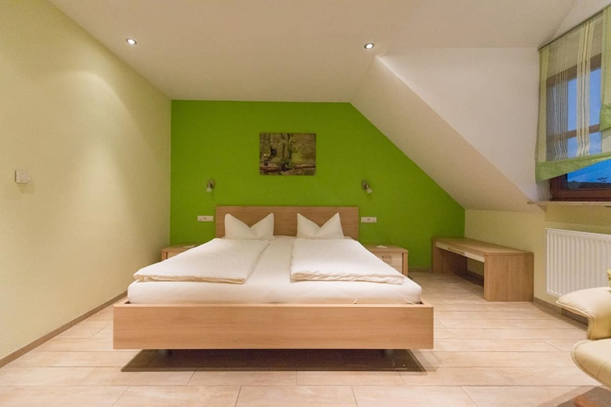 A bedroom with a bed, bedside tables, a bench, and a painting on the wall.