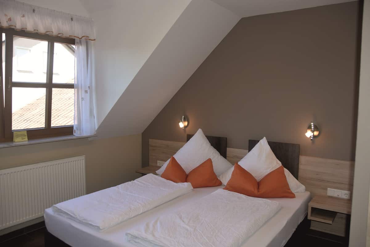 A bedroom with two beds, a window with curtains, and two wall-mounted lights.