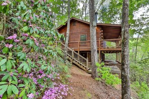 Une cabane dotée d’une terrasse en bois et d’un escalier menant à un deuxième niveau.