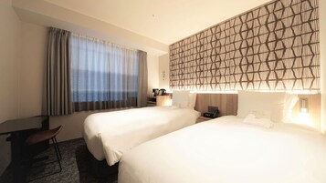 A hotel room with two beds, a desk, a chair, and a large window with curtains.