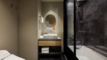 A modern bathroom with a large mirror, a sink, and a glass-enclosed shower.