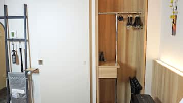A compact bathroom with a wooden vanity, a towel rack, and a small shelf.