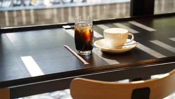 Una mesa con un vaso de té helado y una taza blanca sobre un platito.