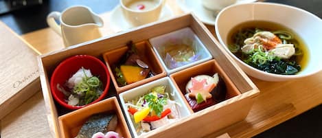A wooden tray with various food items and a bowl of soup.