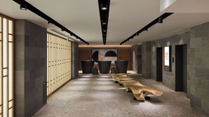 A modern hallway with a long wooden bench, stone walls, and a large abstract painting on the wall.