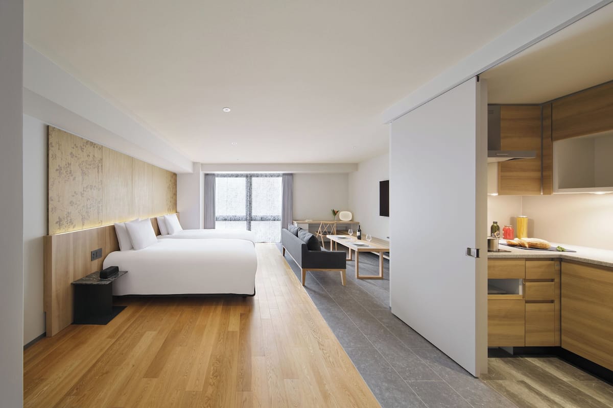 Une chambre d’hôtel moderne équipée d’un grand lit, d’un bureau et d’une kitchenette.