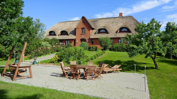 Il s’agit d’un bâtiment traditionnel doté d’un toit de chaume, entouré d’un jardin bien entretenu et agrémenté d’un espace extérieur aménagé pour s’asseoir.