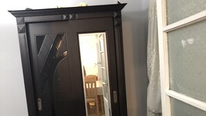 Et værelse med en mørk træskab, et lille bord, en tæppe med mønster og et vindue med matteret glas.