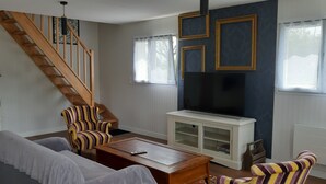 Ein Wohnzimmer mit Treppe, Fernseher und Sofa.