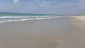 Ein Strand mit breitem Sandstrand und sanften Wellen.